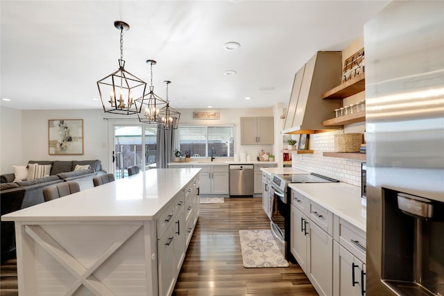 kitchen featuring stainless steel appliances, backsplash, hanging light fixtures, a center island, and dark hardwood / wood-style flooring