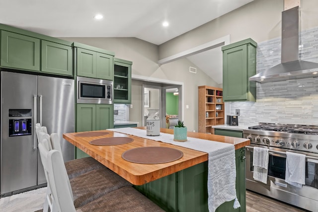 kitchen with lofted ceiling, high quality appliances, green cabinetry, and backsplash