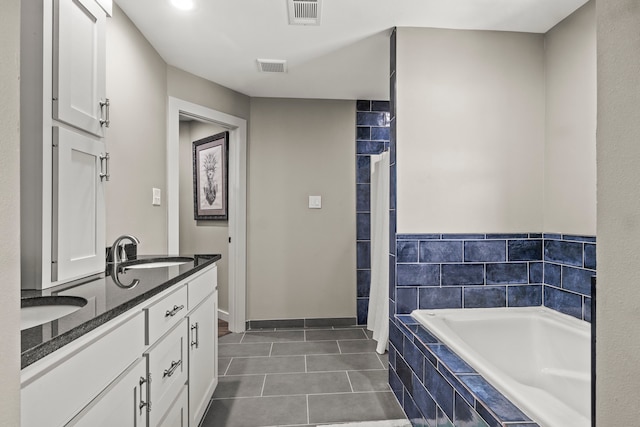 bathroom with vanity, a relaxing tiled tub, and tile patterned floors