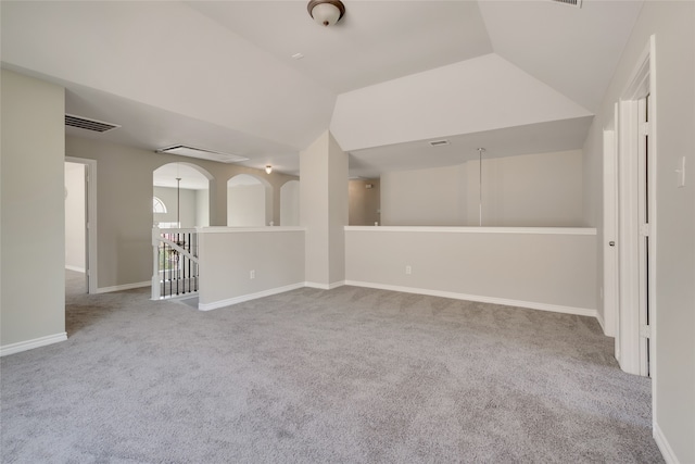 carpeted empty room with vaulted ceiling