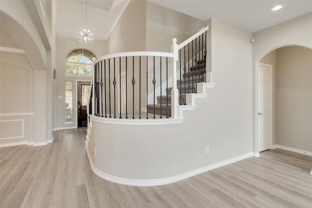 stairs with hardwood / wood-style flooring, an inviting chandelier, and a high ceiling