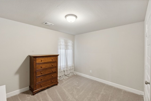 bedroom featuring light carpet and a textured ceiling