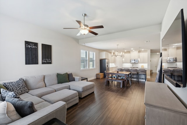 living room featuring ceiling fan with notable chandelier and dark hardwood / wood-style flooring