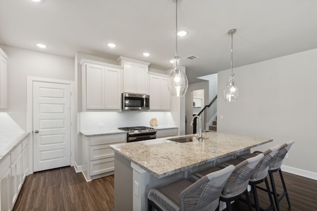 kitchen featuring appliances with stainless steel finishes, sink, decorative light fixtures, and a center island with sink