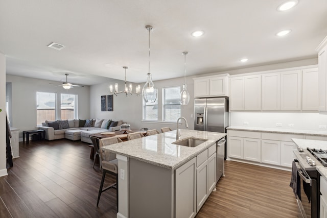 kitchen with white cabinets, a center island with sink, dark hardwood / wood-style flooring, appliances with stainless steel finishes, and sink