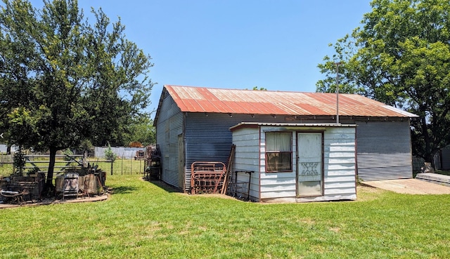 back of property featuring an outdoor structure and a lawn