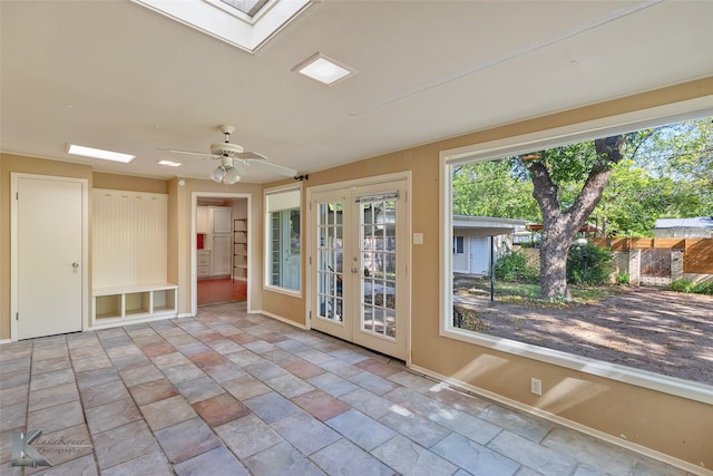 unfurnished sunroom with ceiling fan, a skylight, and french doors