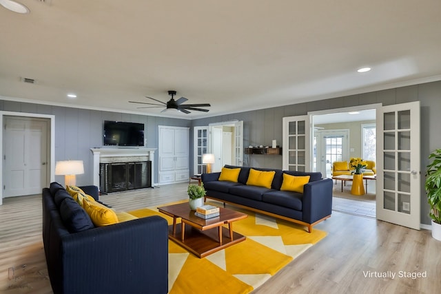 living room featuring a fireplace, french doors, light hardwood / wood-style floors, and ceiling fan