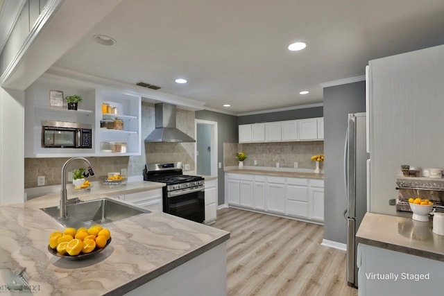 kitchen with stainless steel gas stove, wall chimney exhaust hood, sink, decorative backsplash, and white cabinets