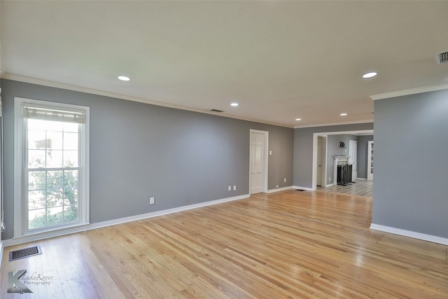 unfurnished room featuring a wealth of natural light, crown molding, and light wood-type flooring