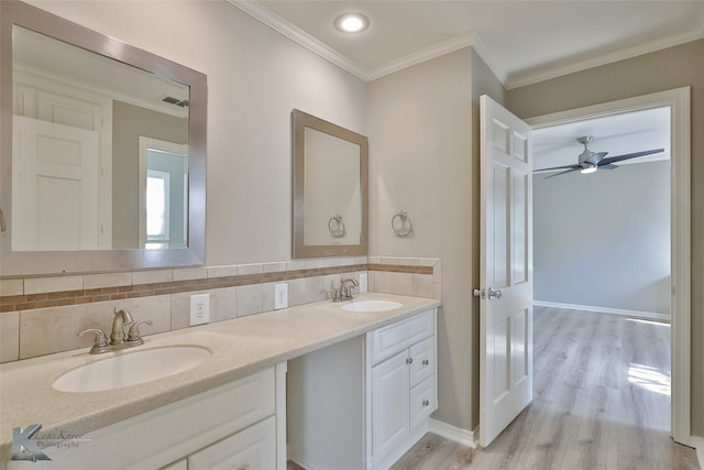 bathroom featuring backsplash, ornamental molding, vanity, ceiling fan, and wood-type flooring