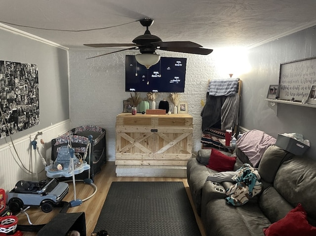 living room with ornamental molding, wood-type flooring, and ceiling fan