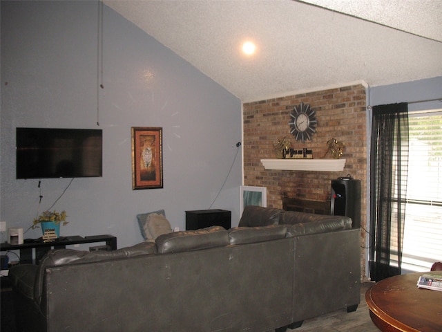 living room featuring a fireplace, hardwood / wood-style floors, a textured ceiling, and vaulted ceiling