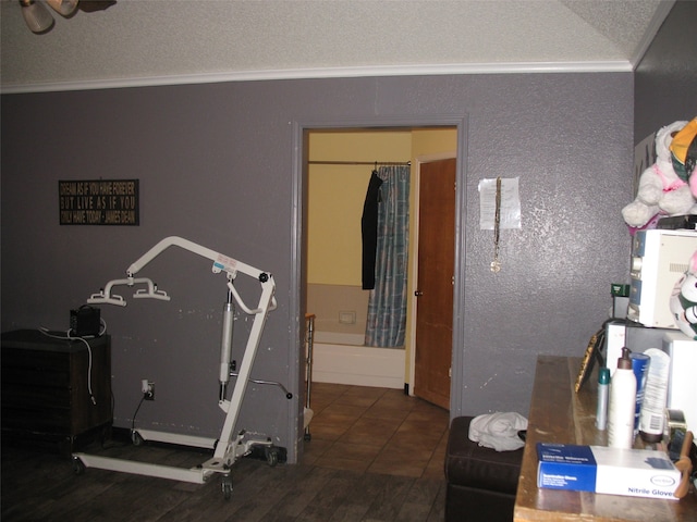 exercise room featuring dark wood-type flooring, a textured ceiling, and ornamental molding