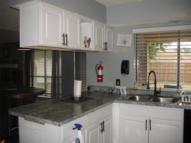 kitchen with white cabinetry, sink, a textured ceiling, and kitchen peninsula