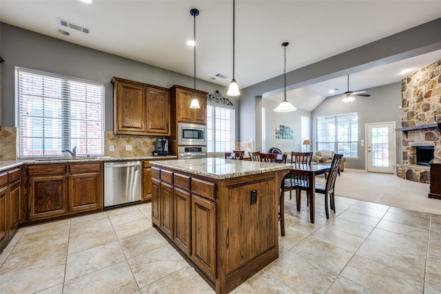 kitchen featuring a kitchen island, backsplash, ceiling fan, stainless steel appliances, and pendant lighting