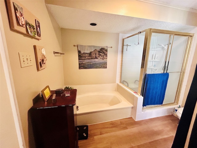 bathroom with a textured ceiling, plus walk in shower, and hardwood / wood-style floors