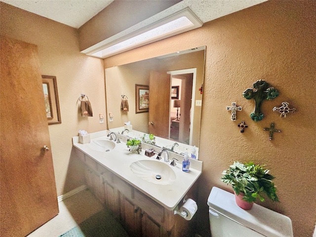 bathroom with vanity, toilet, and a textured ceiling