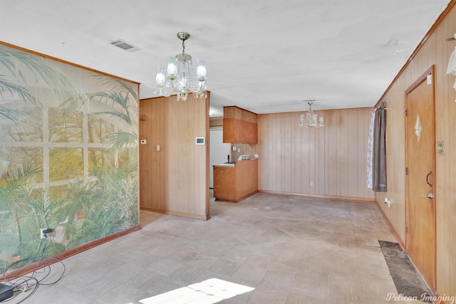 interior space with wood walls, a chandelier, and hanging light fixtures