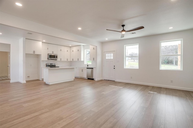 unfurnished living room with ceiling fan and light hardwood / wood-style flooring