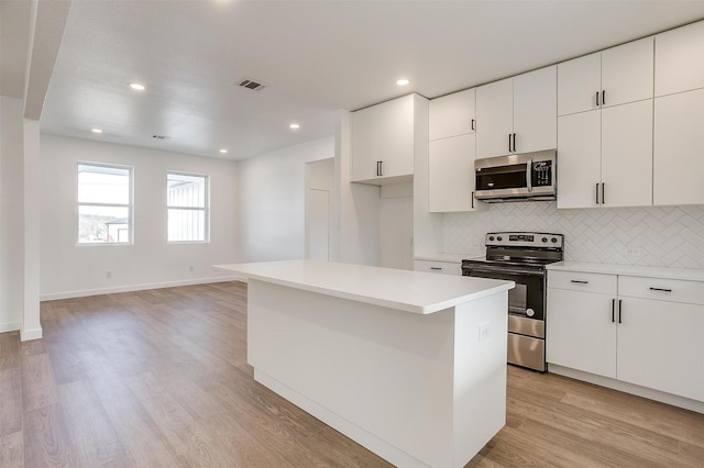 kitchen featuring tasteful backsplash, light hardwood / wood-style floors, a kitchen island, white cabinetry, and appliances with stainless steel finishes