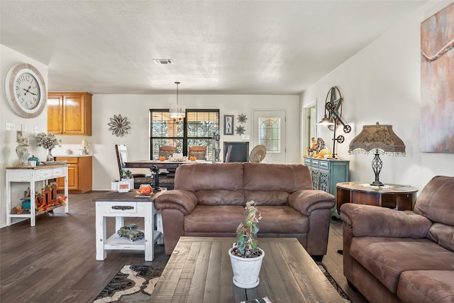 living room featuring dark wood-style floors, visible vents, and an inviting chandelier