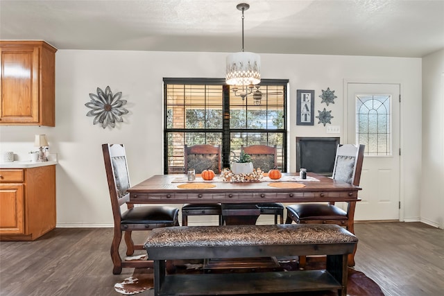 dining space with baseboards, a chandelier, and dark wood-style flooring