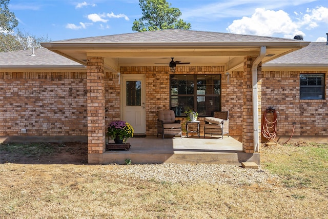 property entrance with a shingled roof, brick siding, and ceiling fan