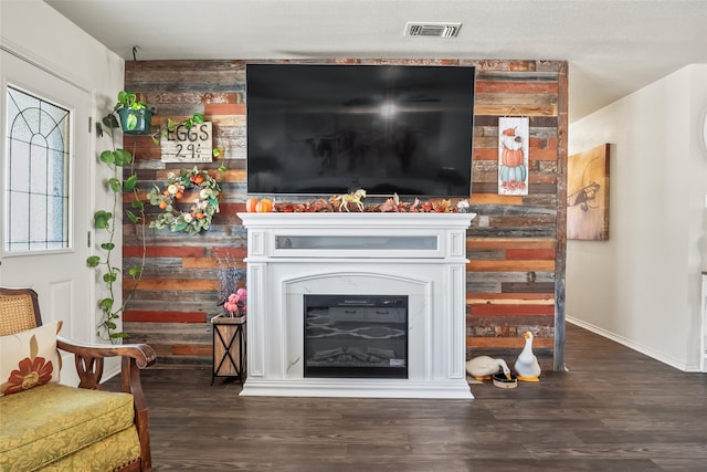 living area with baseboards, visible vents, wood finished floors, and a glass covered fireplace