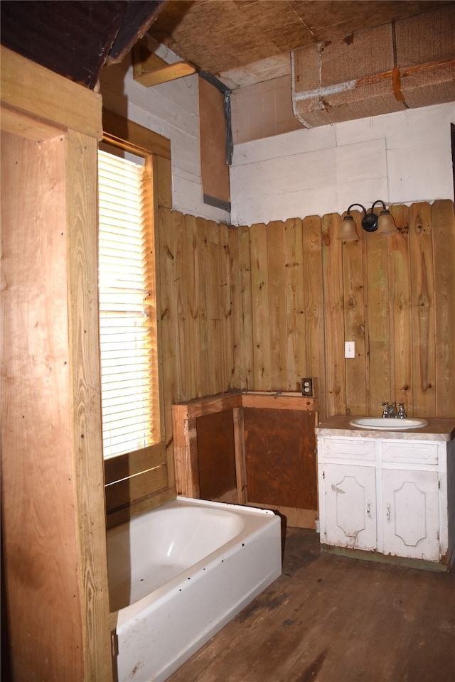 bathroom featuring vanity, wooden walls, a bathtub, and hardwood / wood-style flooring