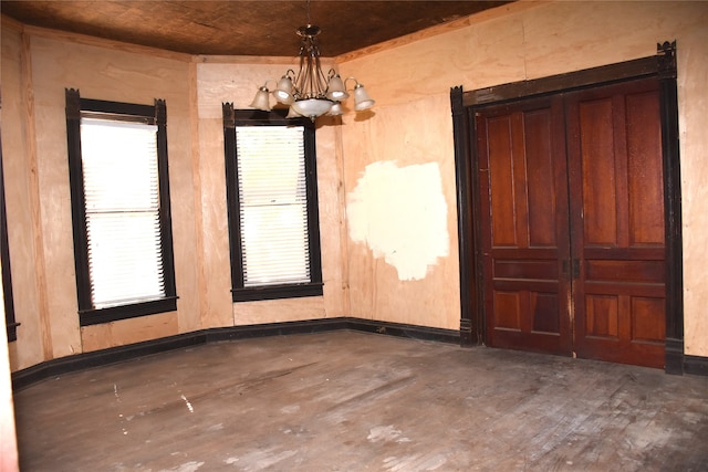 spare room with a chandelier, wood ceiling, dark hardwood / wood-style floors, and wood walls