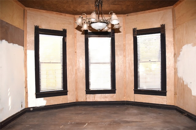 unfurnished room with concrete floors and a chandelier