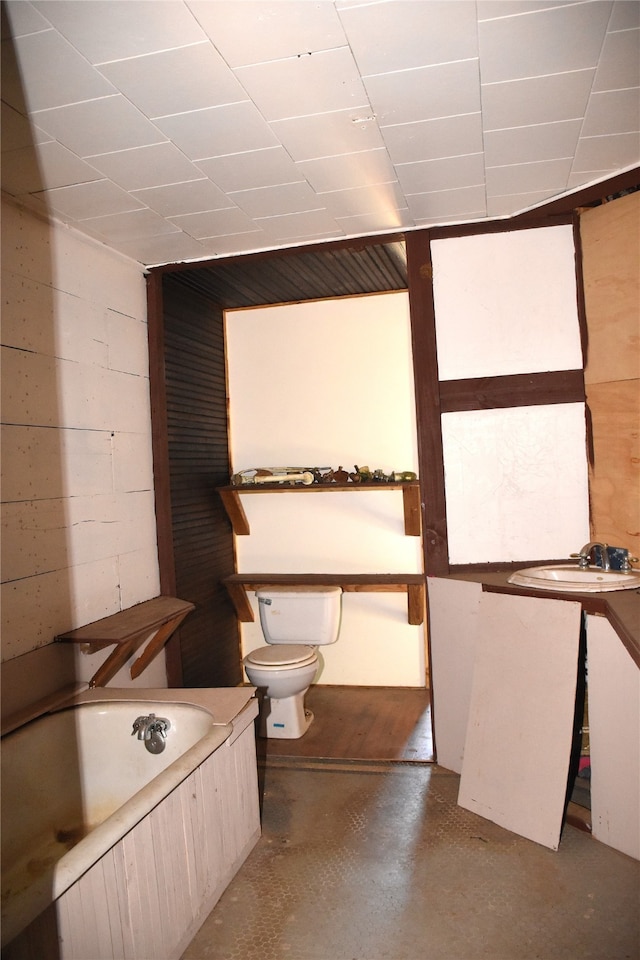 bathroom with toilet, a tub, and concrete floors