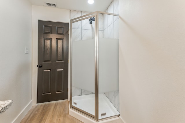 bathroom featuring hardwood / wood-style flooring and a shower with door