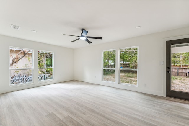 empty room featuring a wealth of natural light, ceiling fan, and light wood-type flooring