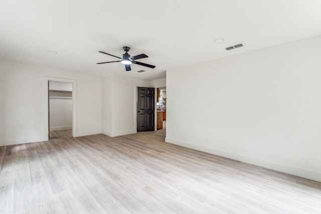 interior space with a walk in closet, ceiling fan, a closet, and light hardwood / wood-style floors