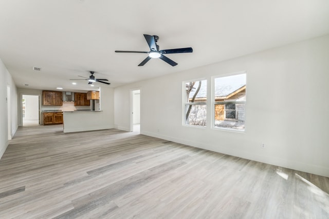 unfurnished living room featuring ceiling fan and light hardwood / wood-style floors