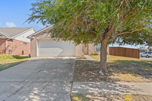 view of front of house featuring a garage, driveway, brick siding, and fence