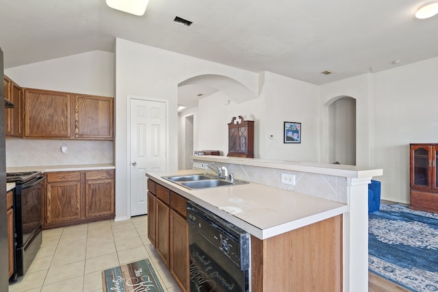 kitchen featuring decorative backsplash, an island with sink, light tile patterned floors, black appliances, and sink