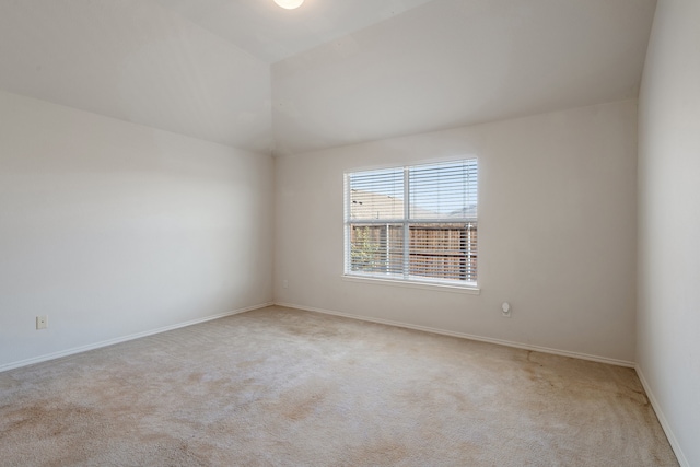 unfurnished room with light carpet, vaulted ceiling, and baseboards