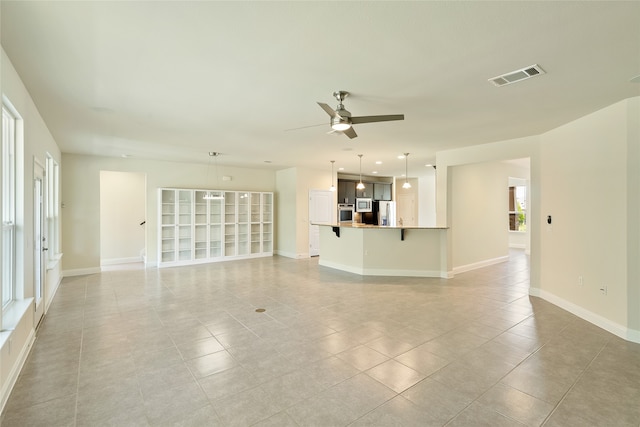 unfurnished living room featuring ceiling fan, plenty of natural light, and light tile patterned floors