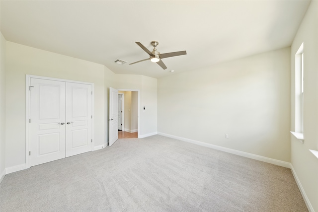 unfurnished bedroom with a closet, light colored carpet, and ceiling fan