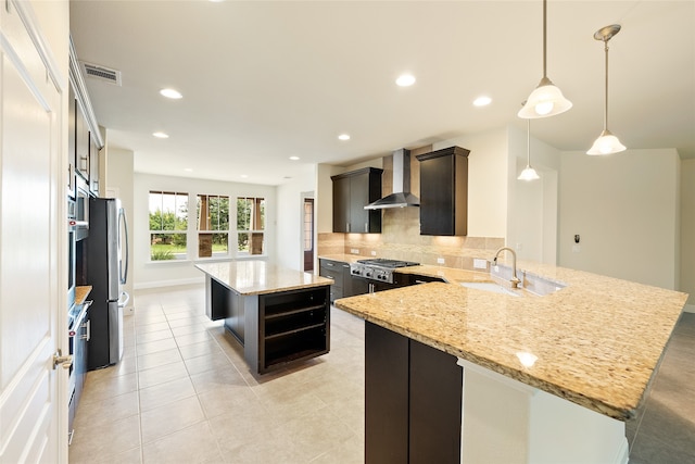 kitchen featuring decorative backsplash, sink, wall chimney range hood, pendant lighting, and a kitchen island