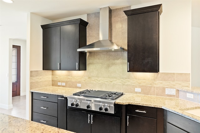 kitchen with tasteful backsplash, light stone counters, wall chimney exhaust hood, stainless steel gas stovetop, and light tile patterned flooring