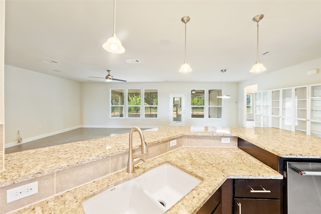 kitchen featuring ceiling fan, sink, pendant lighting, and light stone counters