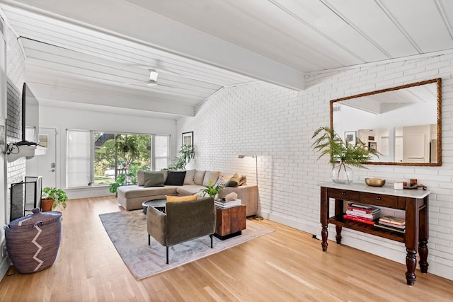 living room featuring wooden ceiling, brick wall, lofted ceiling with beams, light wood-type flooring, and a fireplace