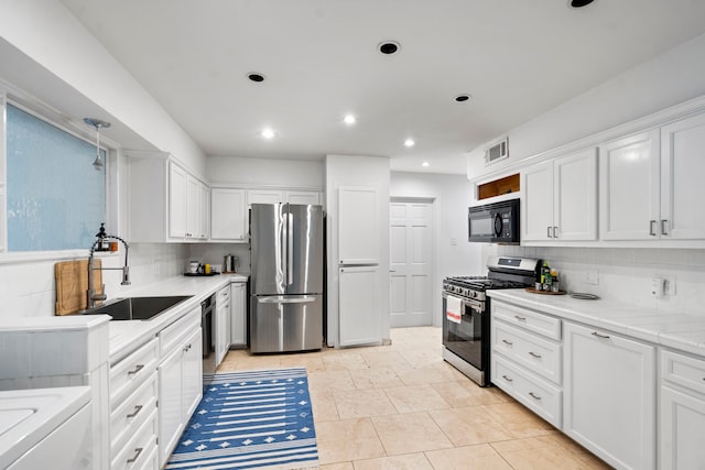 kitchen featuring white cabinetry, black appliances, sink, and decorative backsplash