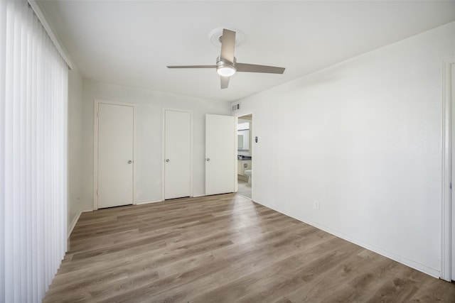 unfurnished bedroom with multiple closets, ceiling fan, and light wood-type flooring