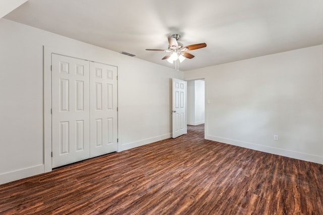 unfurnished bedroom with dark wood-type flooring, a closet, and ceiling fan