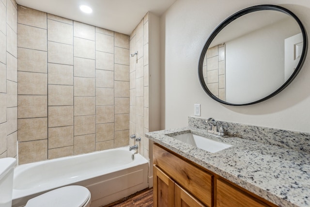 full bathroom featuring vanity, tiled shower / bath combo, wood-type flooring, and toilet